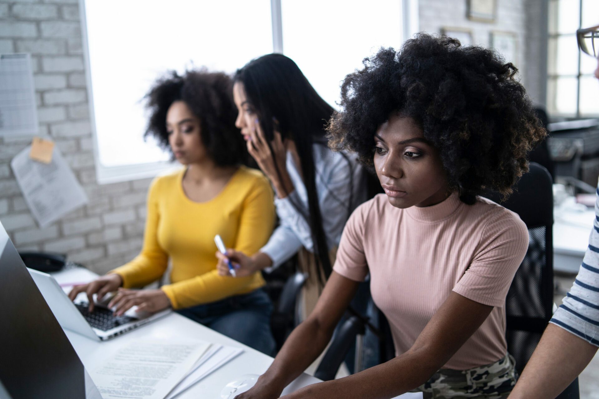 Image of three business women working on a computer.